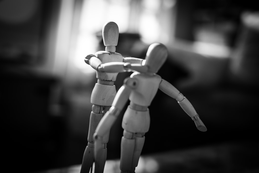 Black and white photograph of two wooden artist's mannequins positioned to look as though they are having a disagreement